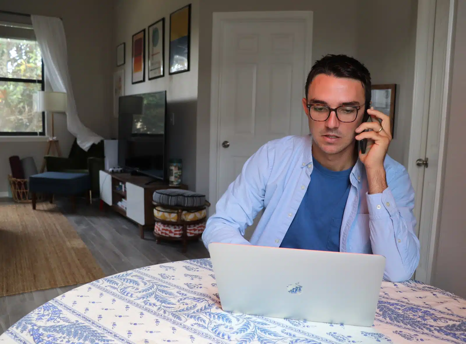 man in white dress shirt wearing eyeglasses sitting by the table using macbook